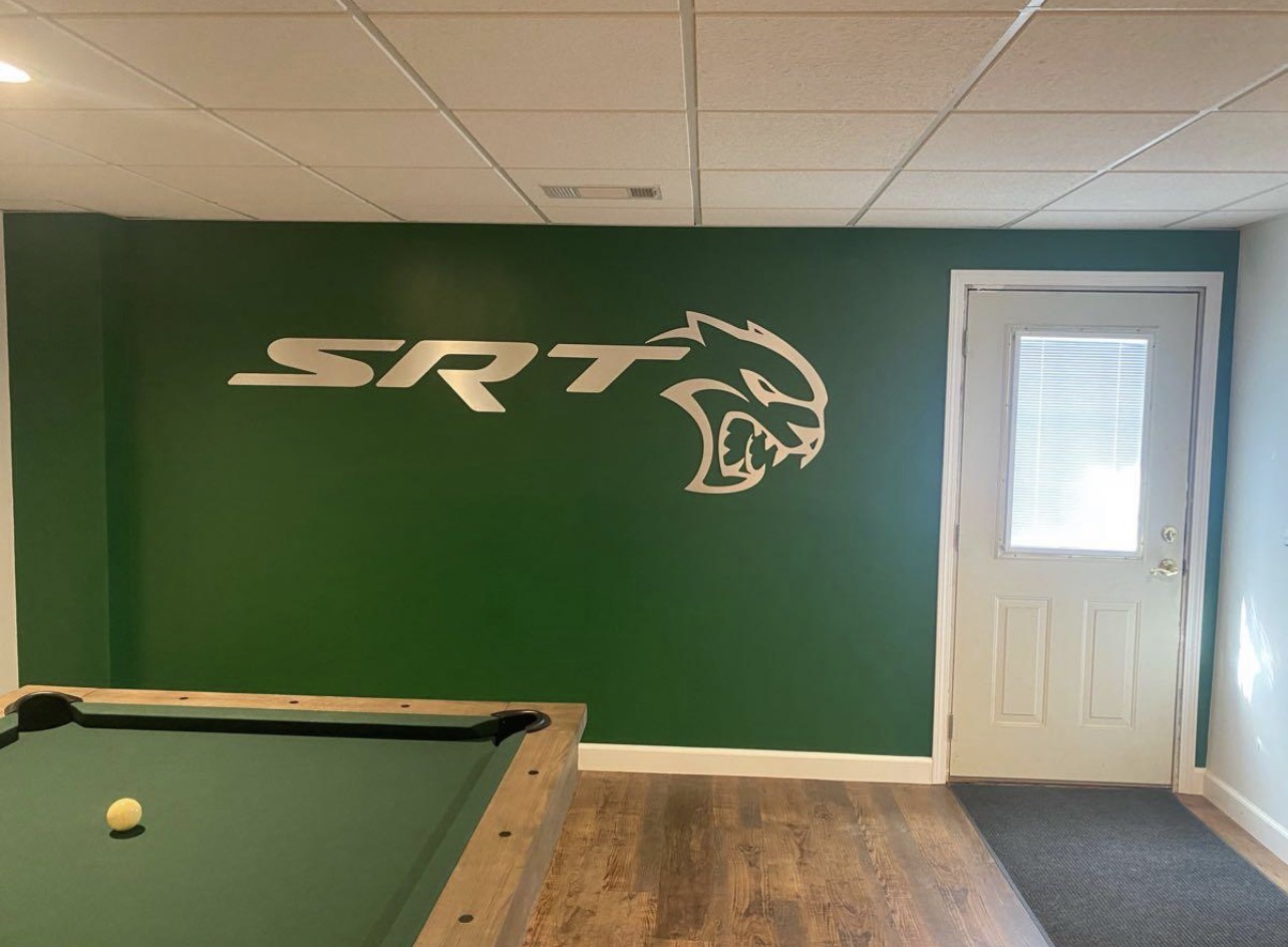 Green accent wall with a custom painted logo in a game room