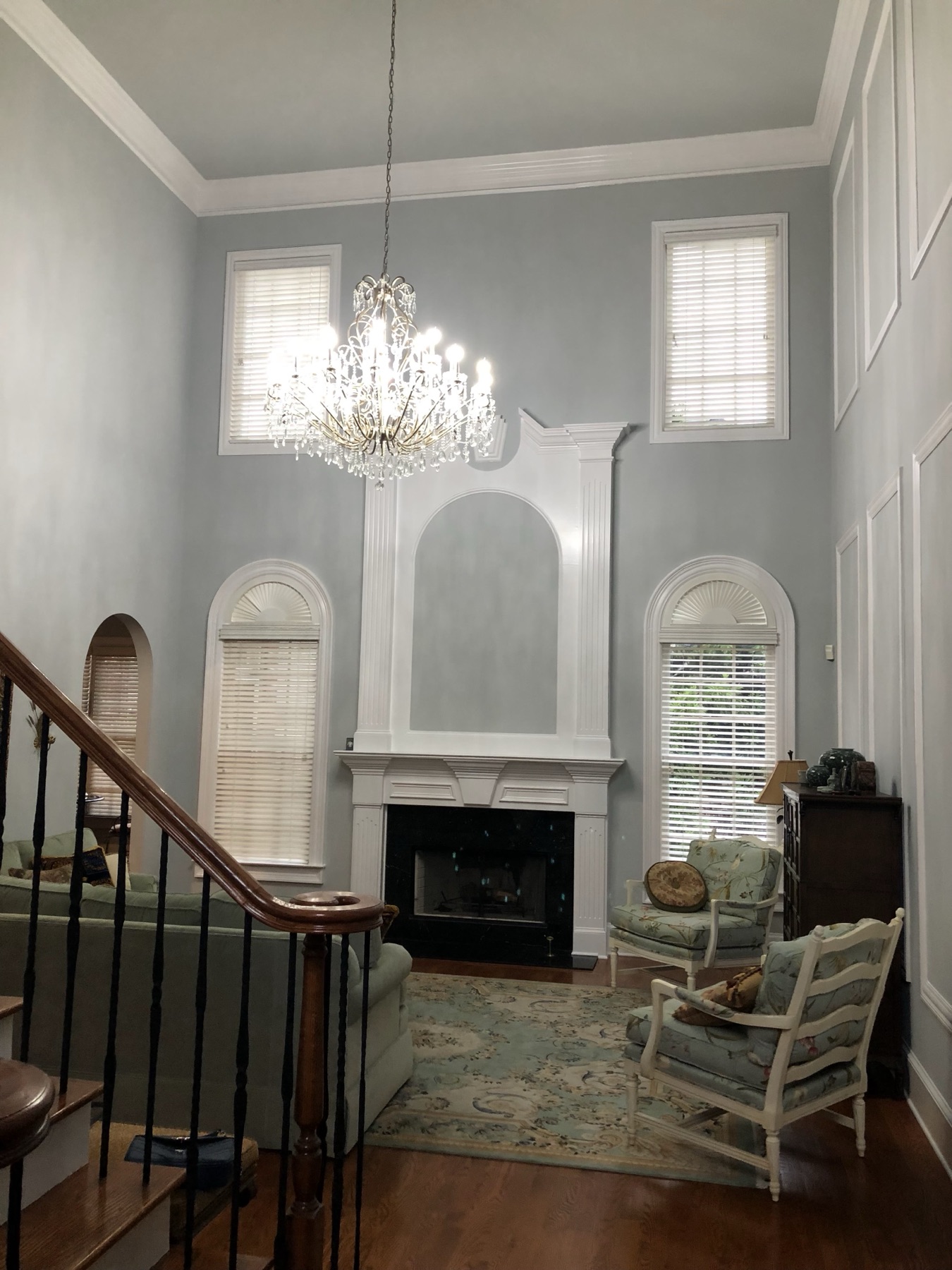 Two-story great room with a white fireplace surround and soft gray walls