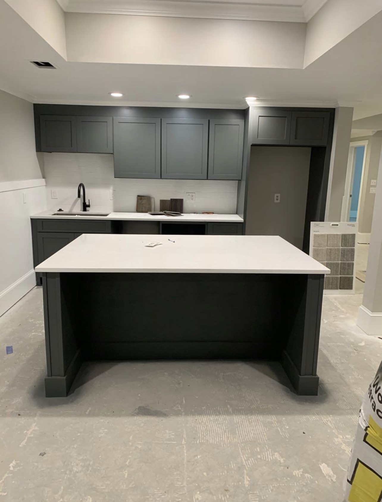 Kitchen with dark green painted cabinets and white island